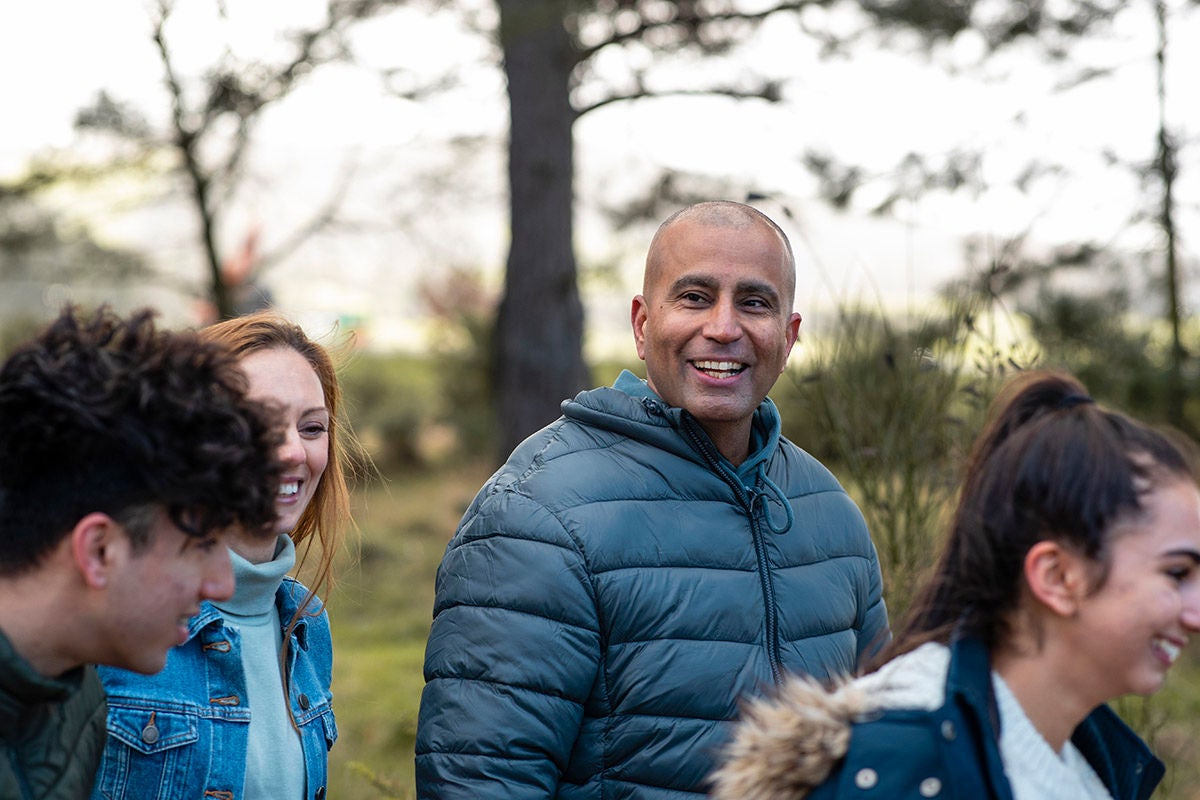 Group of people standing together outdoors in a wooded park area.