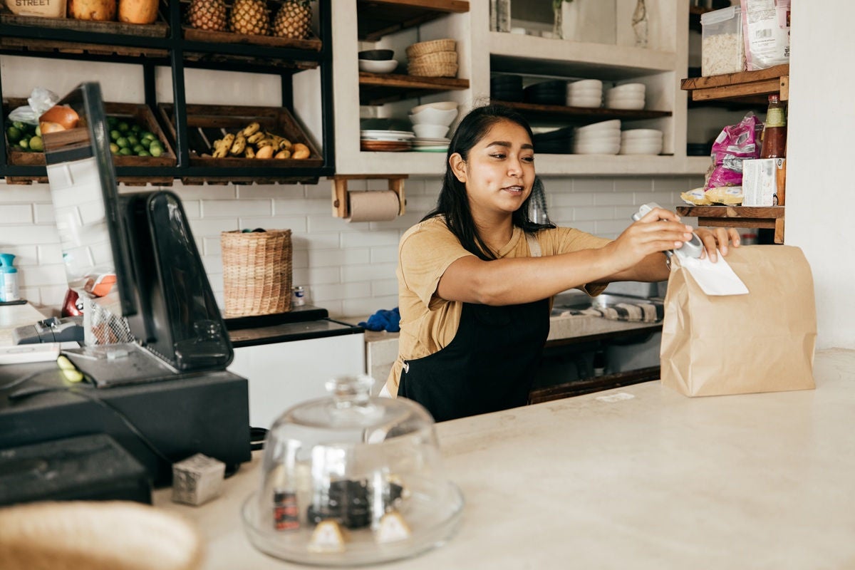 Small business owner packing takeaway order at grocery counter