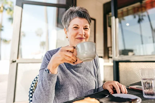 older woman holding a mug and smiling