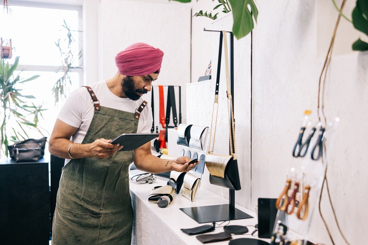 Small business owner managing inventory with a tablet in a boutique store.