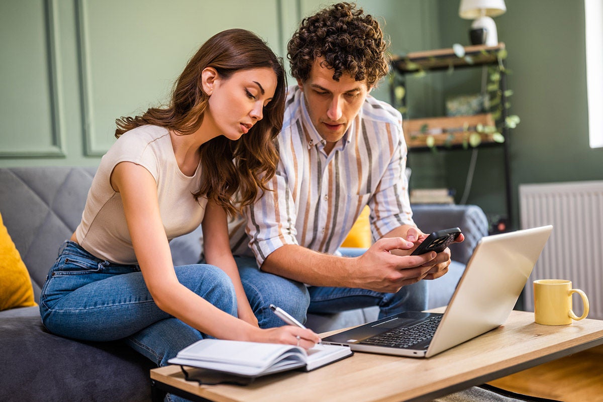 Couple discussing home finance while checking bills. They are checking financial documents and calculating family budget in living room.