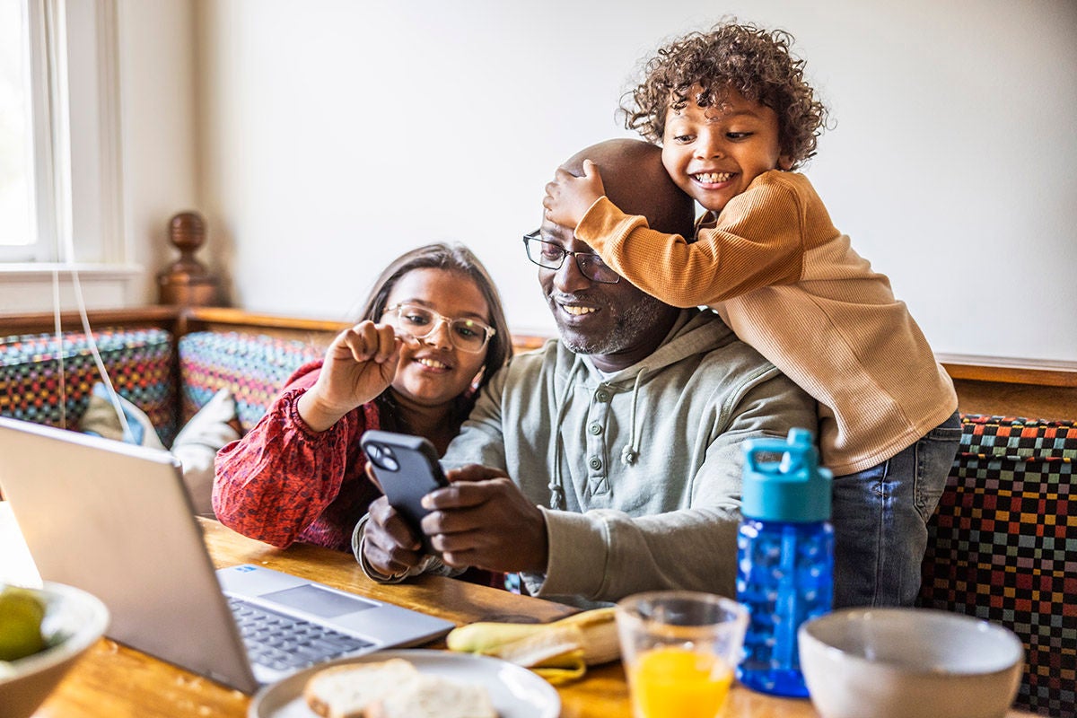 Father multitasking with children at breakfast