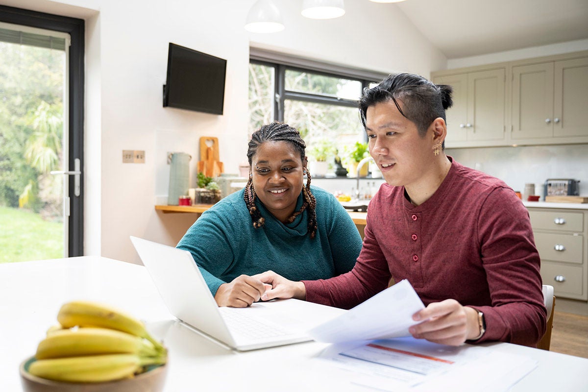 Couple reviewing household bills and budgeting together using laptop at home
