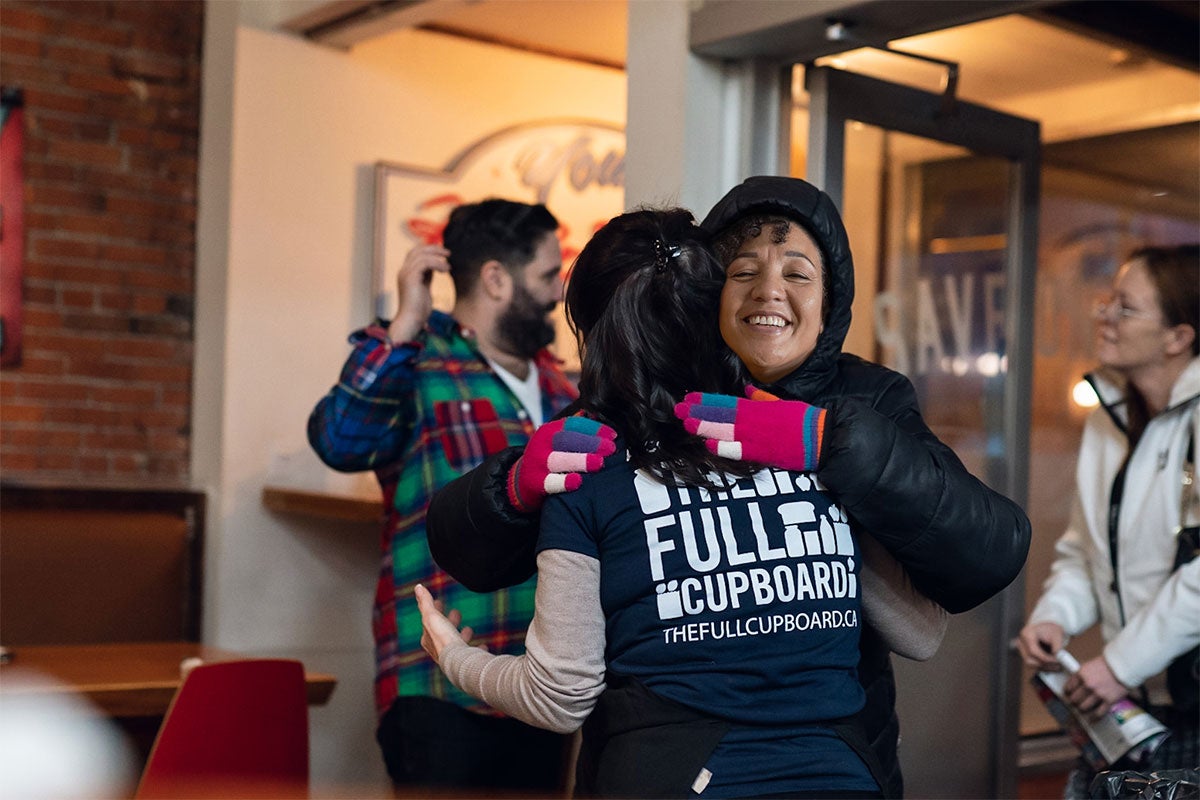 Two community workers hugging each other while volunteering