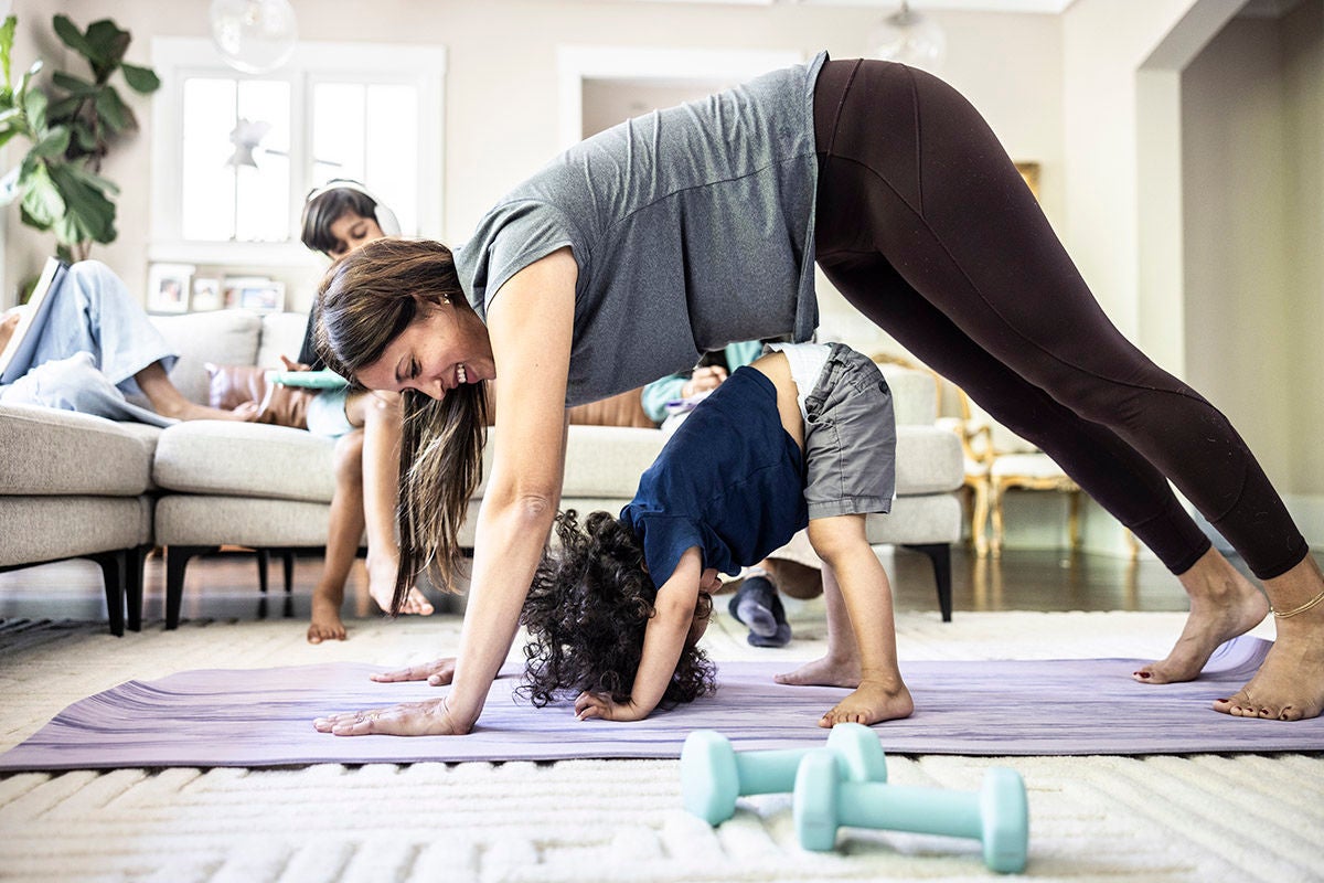 Mother exercising at home while distracted by toddler boy