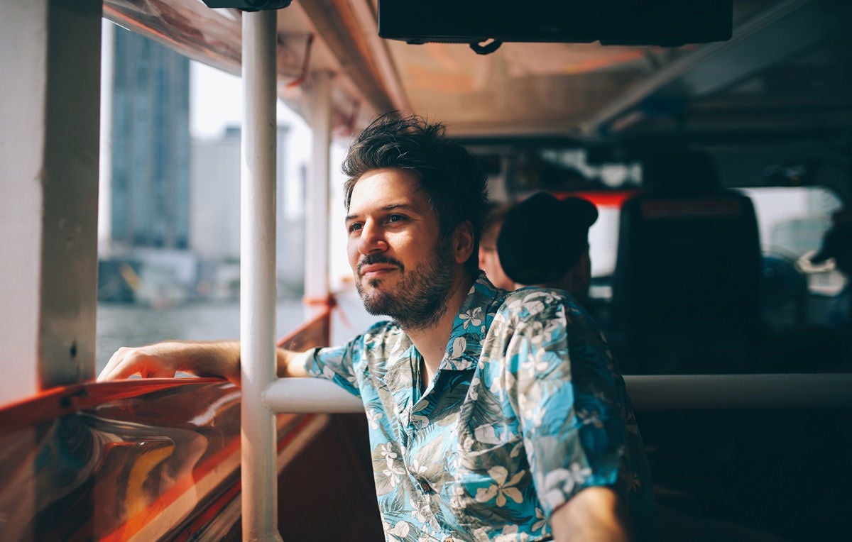 Man in a floral shirt riding a boat and looking out over the water