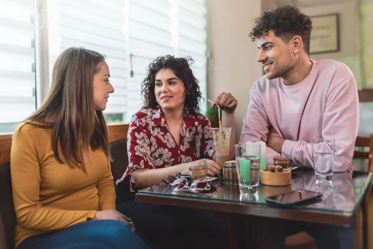 3 friends smiling and talking at a restaurant