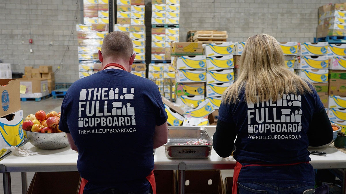 two volunteers prepping food at the food bank