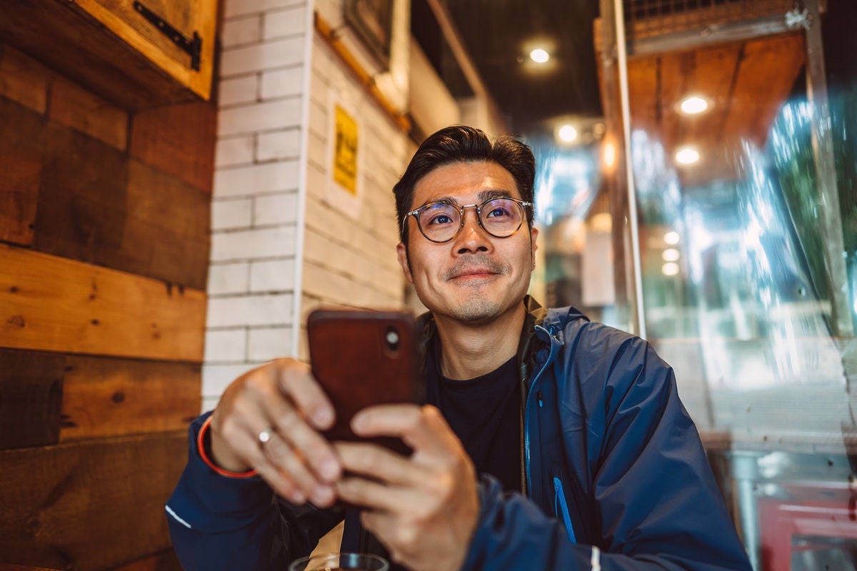 Person using a smartphone inside a cozy café.