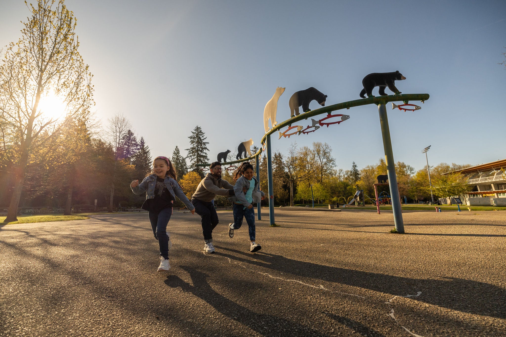 Dad playing with two kids in childrens park during dusk