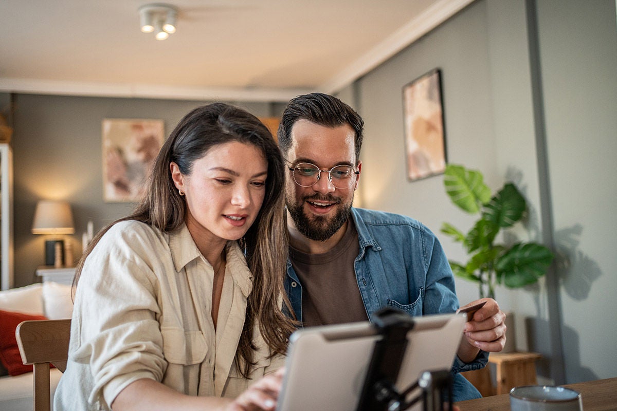 Couple reviewing information on a tablet at home, representing shared financial planning, digital banking, and managing household finances together.