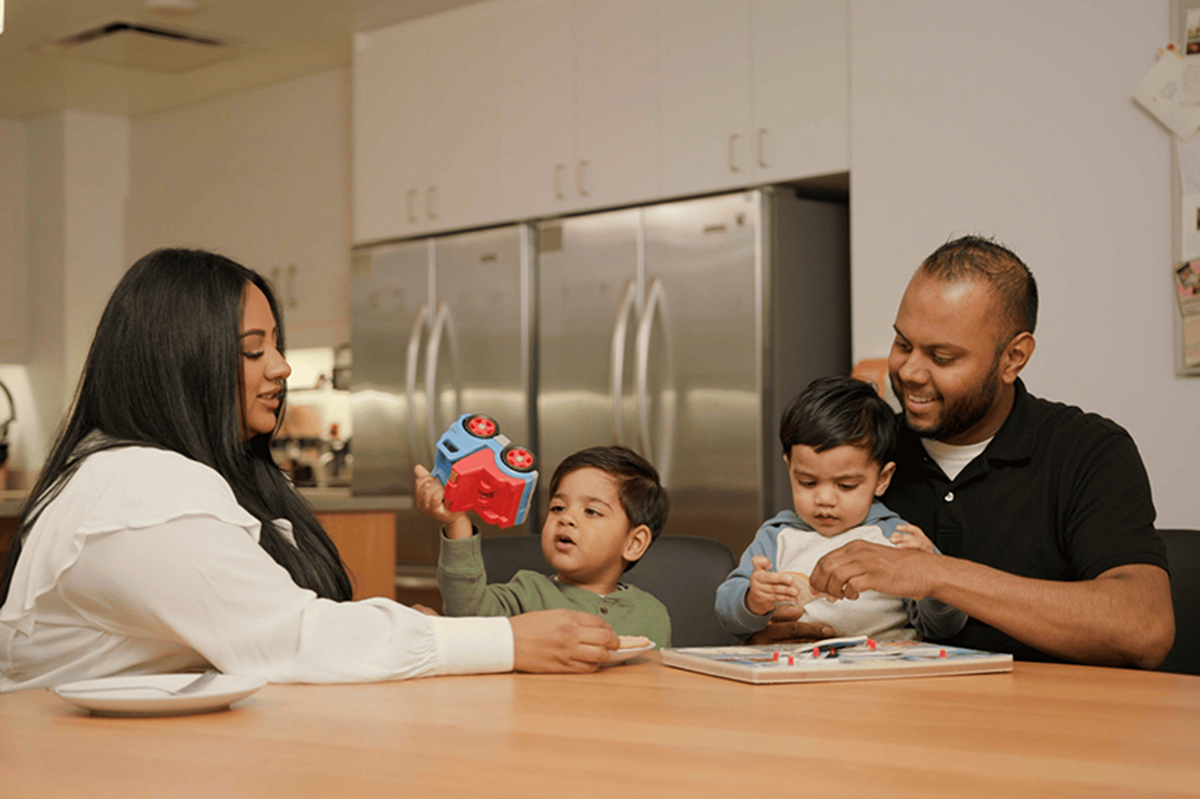 Family seated at a table playing with toys and building blocks in a shared kitchen or family room
