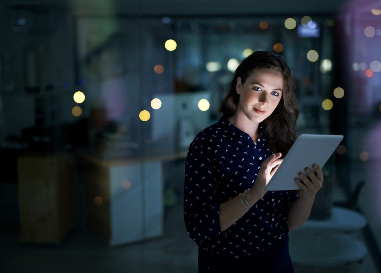 Portrait of a young businesswoman working late on a digital tablet in an office