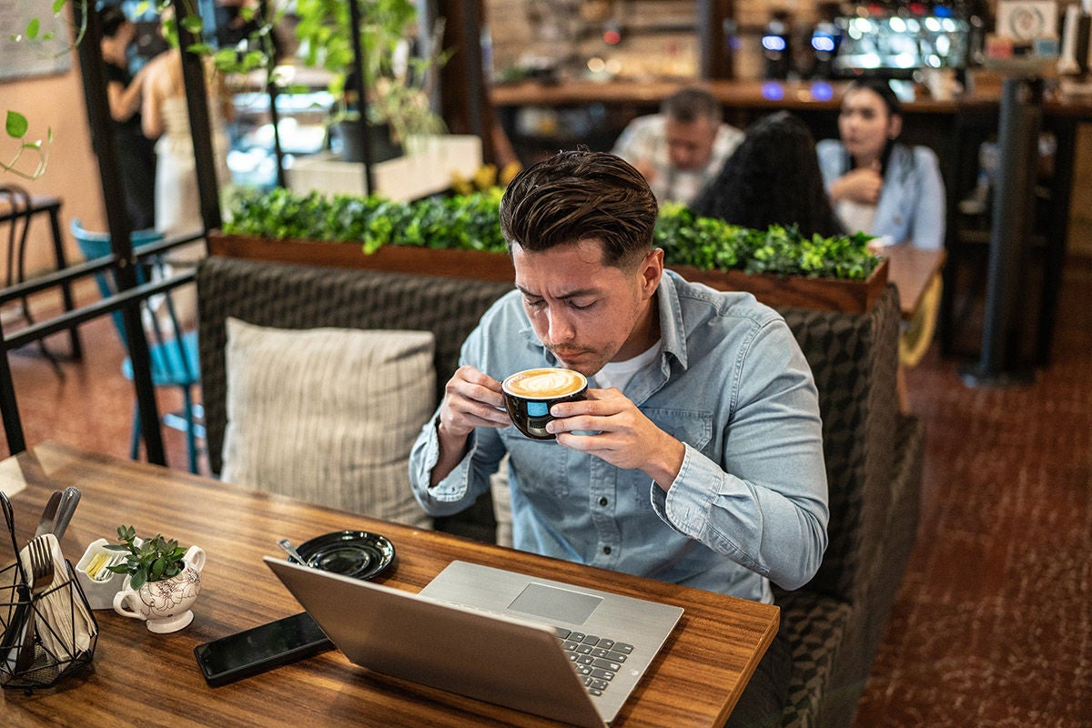 Individual managing personal finances and online banking on laptop while working at a café