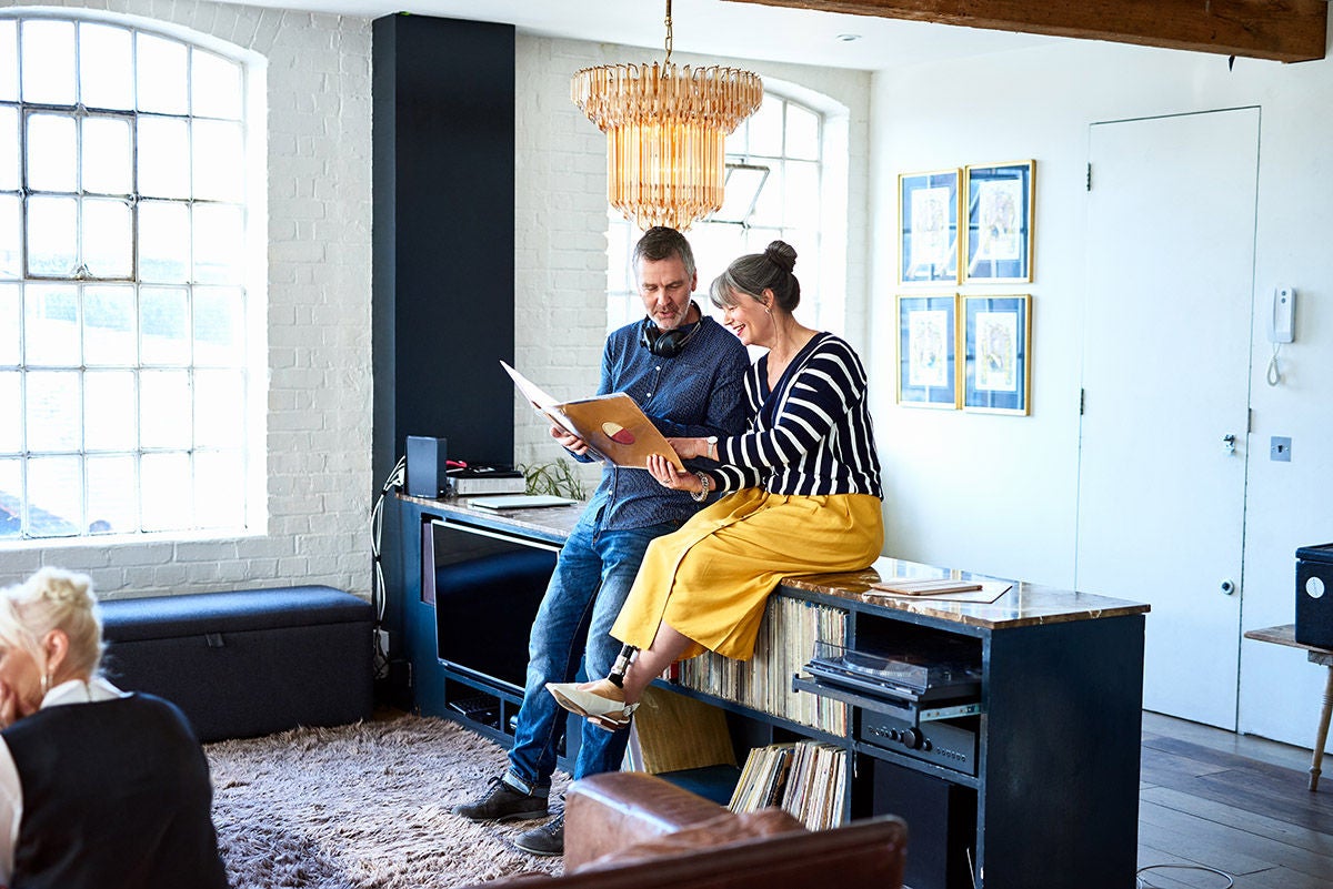 Two people sitting together in a bright, modern living room, looking at an album and talking.