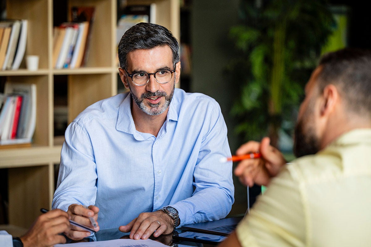Financial advisor meeting with clients at a desk, reviewing documents and discussing personalized banking or investment solutions in a professional office environment.