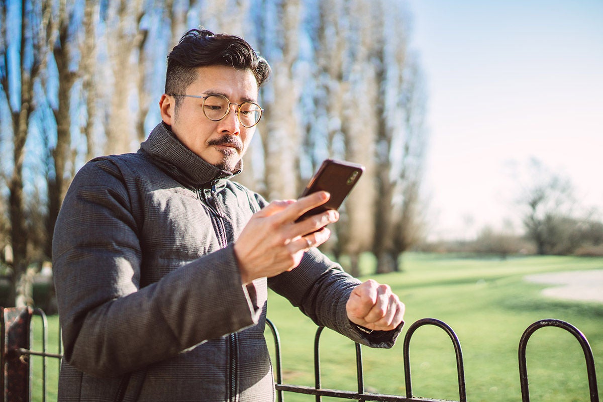 Individual checking a smartphone while outdoors, representing mobile banking, real‑time account access, and managing finances on the go through secure digital banking services.