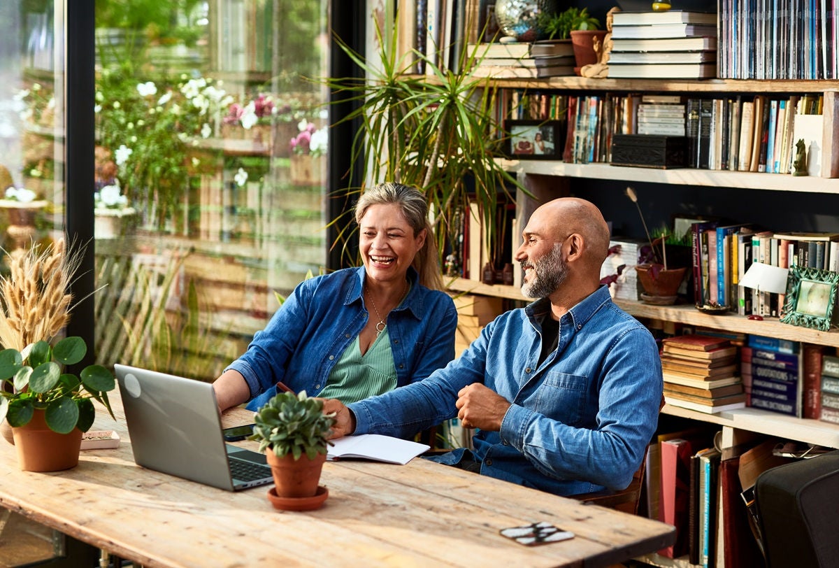 Two people working together at a laptop in a cozy, book‑filled workspace.