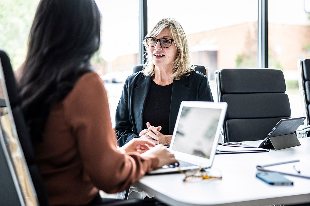Financial advisor meeting with a client at a conference table, with a laptop and documents open during a professional office discussion.