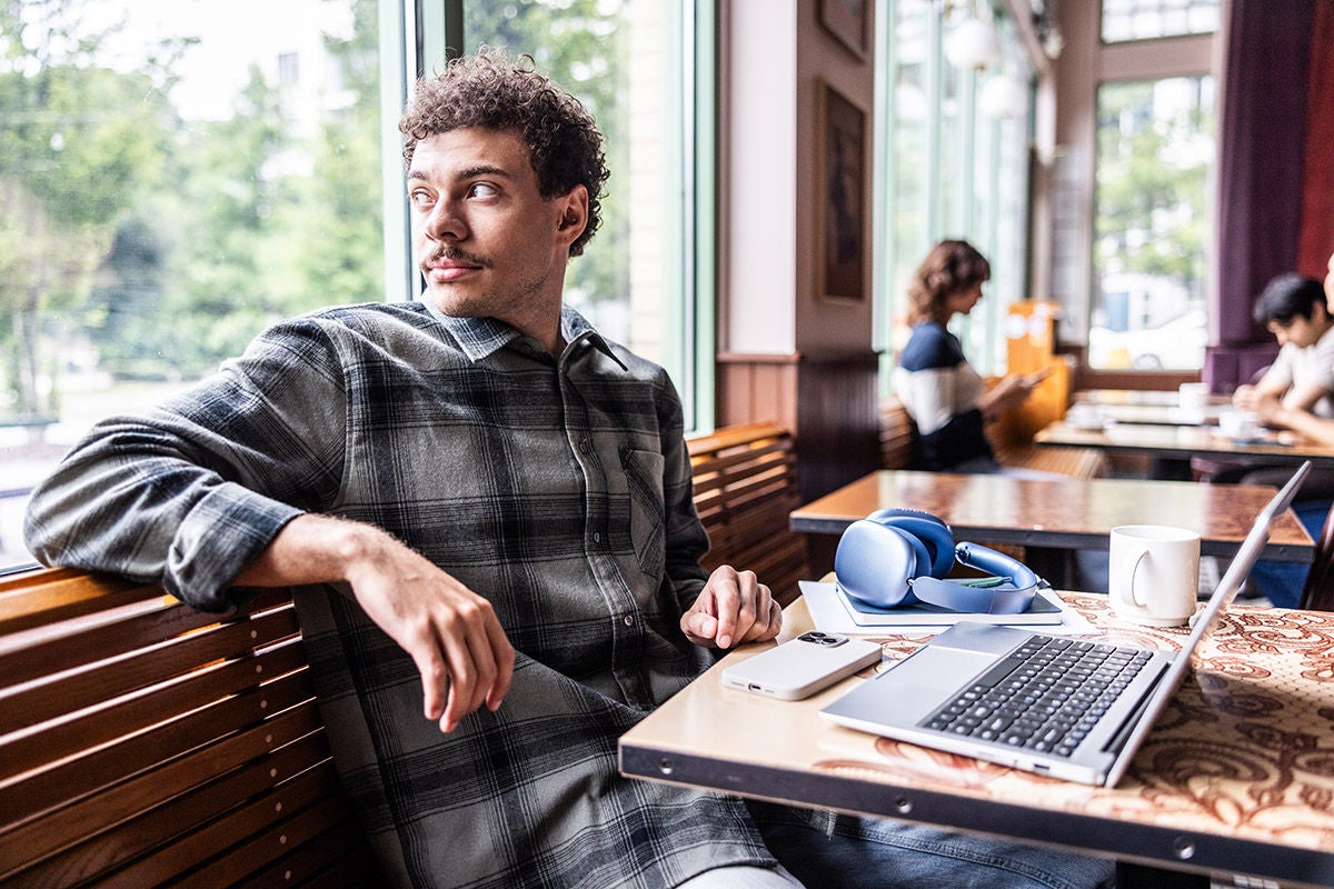 Young man using smartphone and working on laptop in coffeeshop