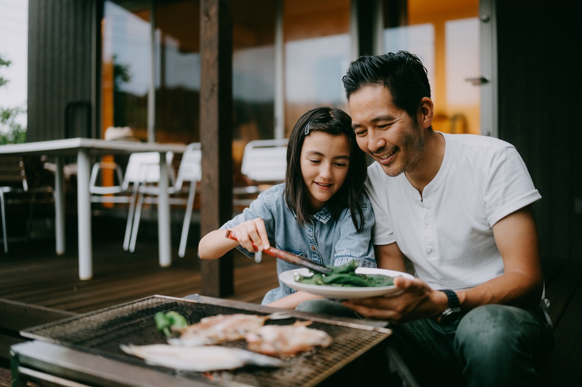 Father and daughter having a barbeque in an outdoor patio.