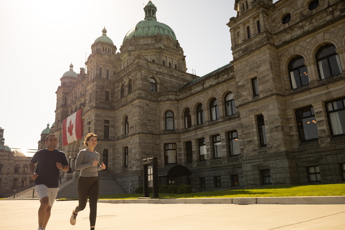 Two people jogging in front of the historic BC parliament building