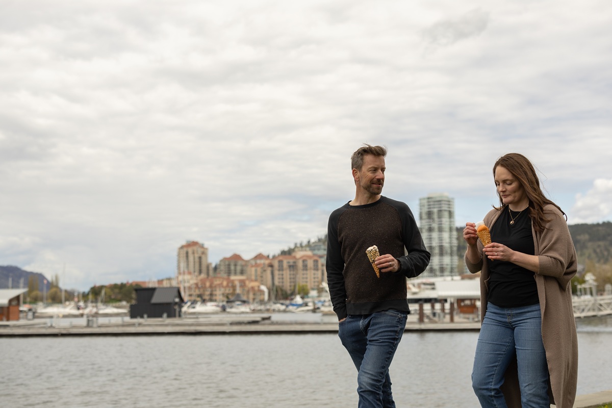 Two people walking by a waterfront marina while eating ice cream cones