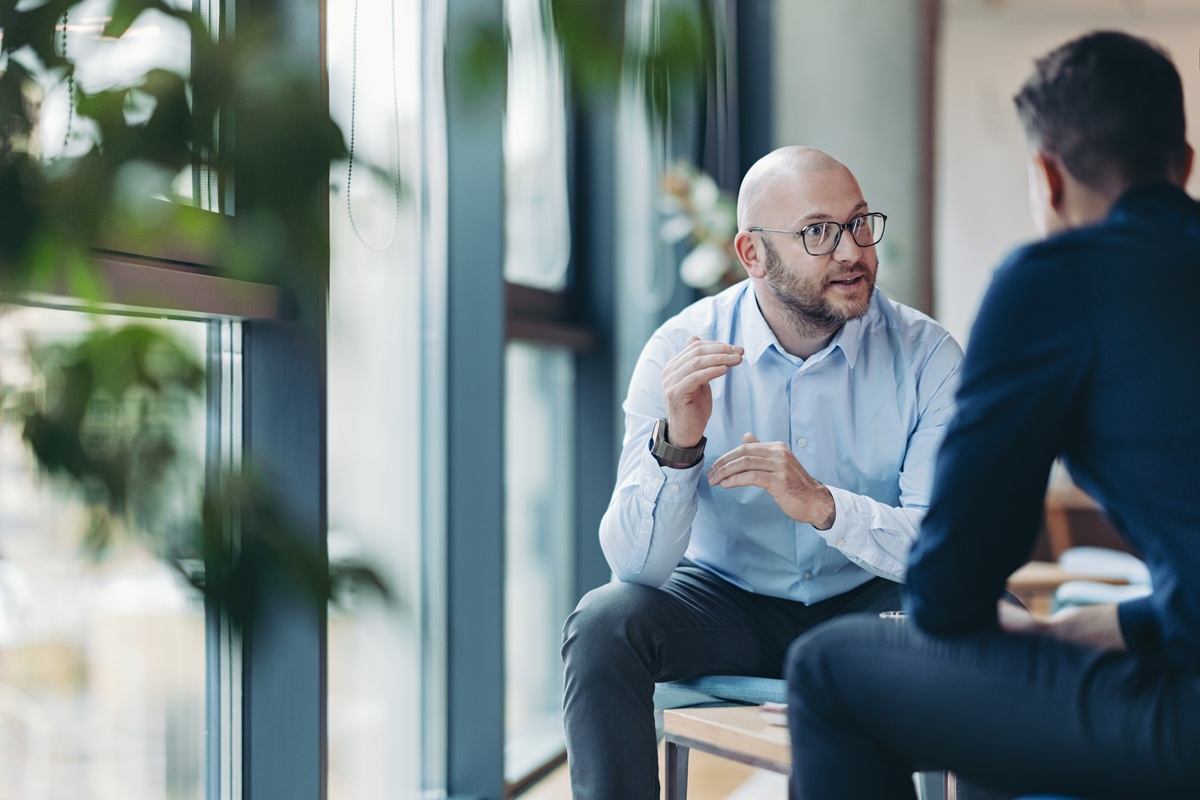 Financial advisor seated near large windows in a modern office, engaged in a focused conversation with a member.