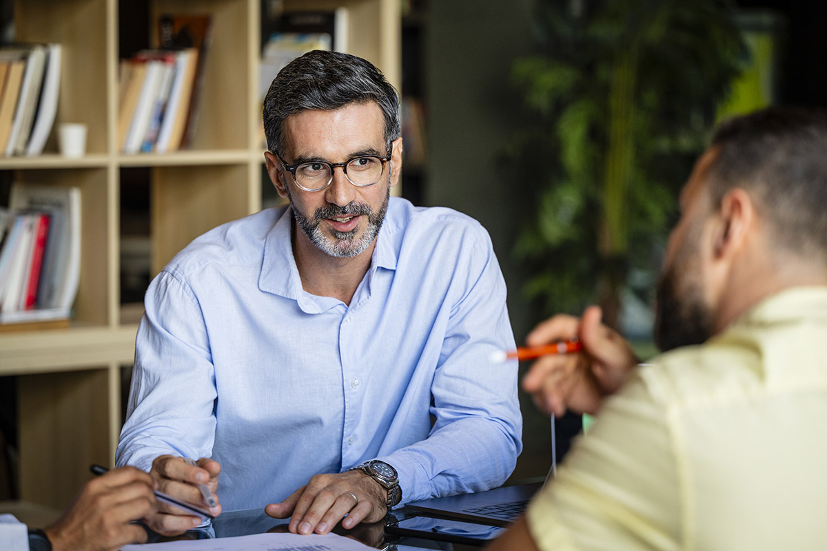 Financial advisor meeting with clients at a desk, reviewing documents and discussing personalized banking or investment solutions in a professional office environment.